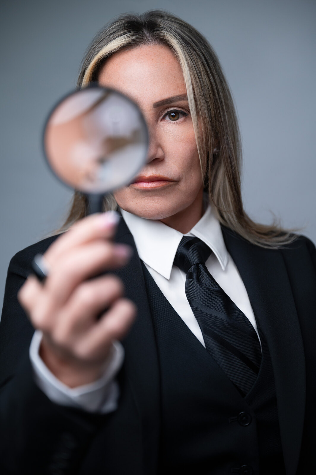 Jovianna Gonzalez of Digital Forensics Now holding a magnifying glass to her eye
